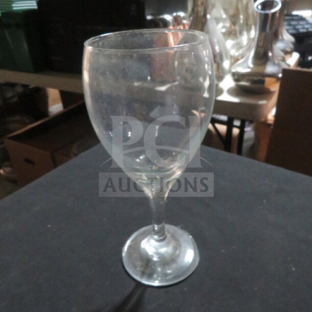 Clear stem wine glass, moderate height, slight wear visible, suitable for various drink types. No visible markings.