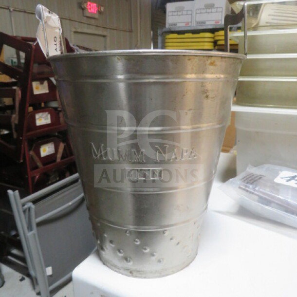 Stainless steel wine bucket with "Mumm Napa" engraving, textured base, used condition, suitable for wine chilling.