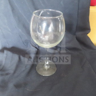 Clear stem wine glass with round bowl, in good condition, set against a dark fabric background. No visible markings.