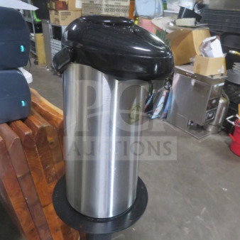 Stainless steel airpot with black lid, used condition, suitable for holding and dispensing beverages.