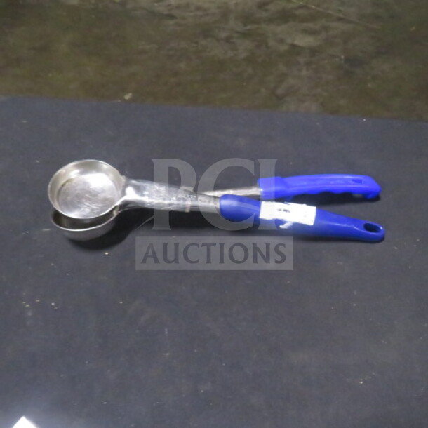 2oz spoodle with metal bowl and blue handle, labeled with “2XBID,” in good condition, used for portion control.