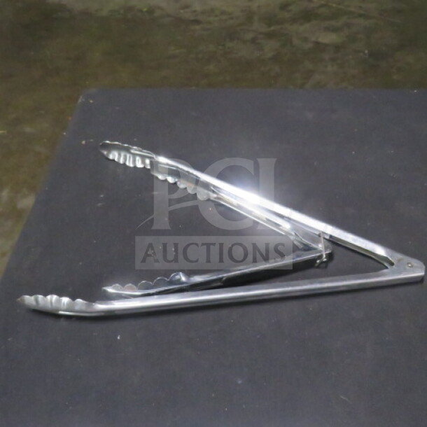 Assorted stainless steel tongs, shiny finish, scalloped edges, used condition, ideal for kitchen or grilling use.