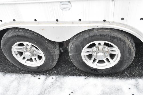 Dual axle of a 24' Cruising Kitchens food trailer, featuring durable steel rims and tires on snowy pavement.