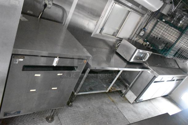Cruising Kitchens 24' food trailer interior with stainless steel counters, commercial fridge, microwave, and appliances.