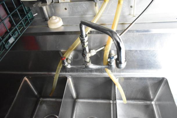 Stainless steel sink with faucet and hoses in Cruising Kitchens 24' food trailer, showing commercial-grade equipment setup.