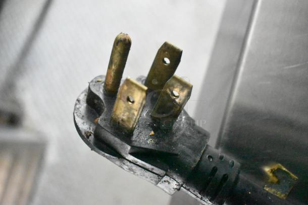 Close-up of an electrical plug from the 2019 Cruising Kitchens 24' food trailer, showing three brass prongs.