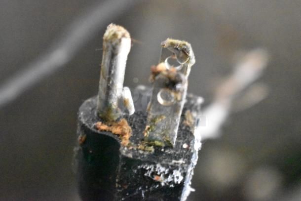 A close-up of a damaged electrical plug with visible rust and frayed wires.