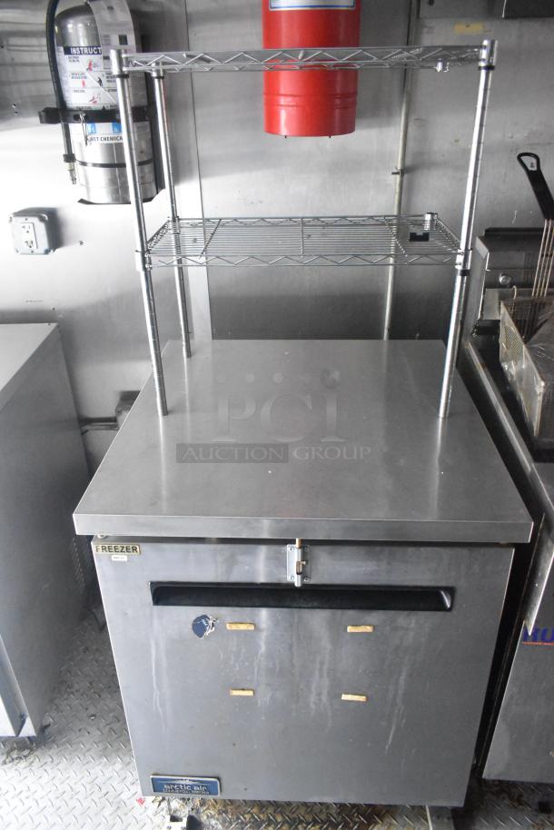 24' Cruising Kitchens food trailer interior with stainless steel surfaces, Arctic Air freezer, shelving, and fire extinguisher.