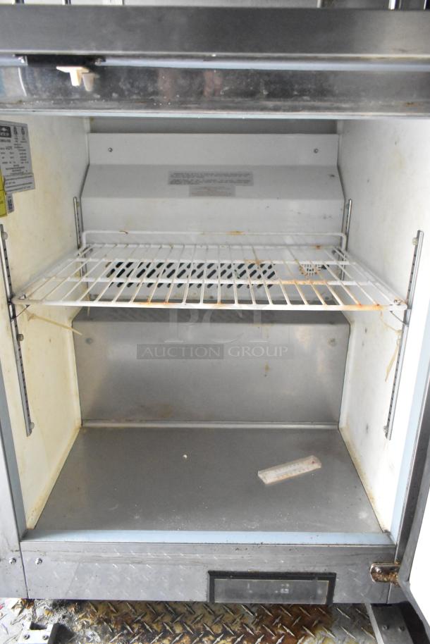 Industrial kitchen appliance inside a Cruising Kitchens 24' food trailer, featuring a metal shelf and a thermometer.