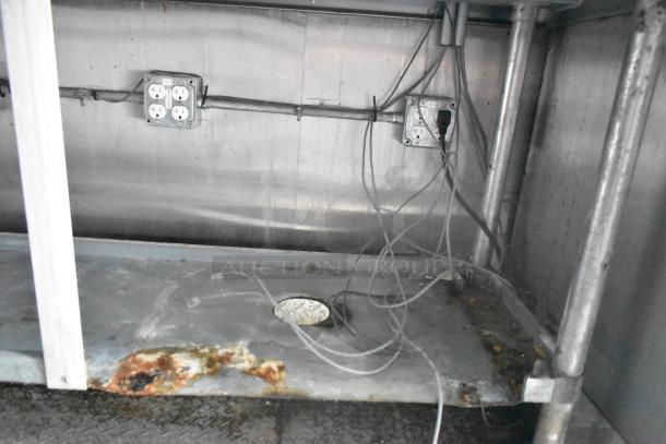 Cruising Kitchens 24' food trailer interior with electrical outlets, cabling, and a metal shelf showing wear.