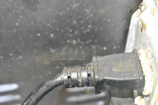 Close-up of a power plug connection on a Cruising Kitchens food trailer, showing a black cable and metal casing.
