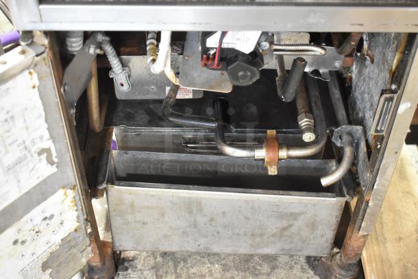 Henny Penny 600 stainless steel pressure fryer, natural gas, on commercial casters. Interior view showing gas connections.