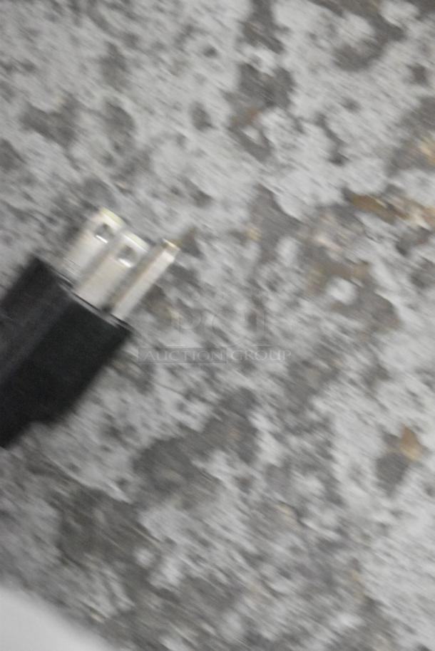 Blurred close-up of an electrical plug on a gray textured surface.