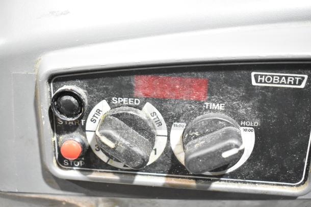 Close-up of Hobart Legacy HL200 mixer controls showing start/stop buttons and speed/time dials, indicating operational settings.