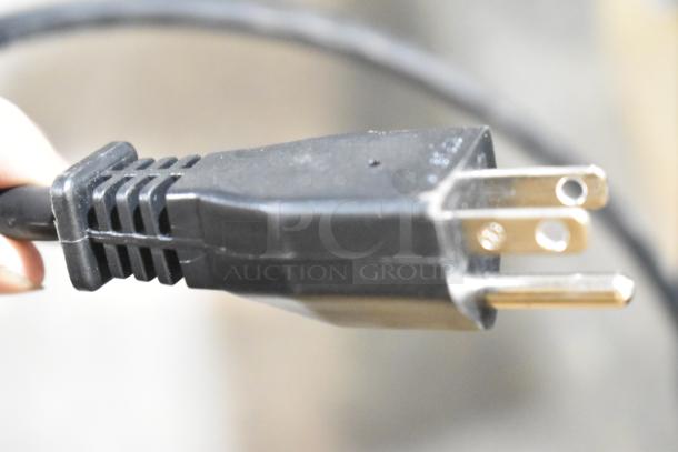 Close-up of a plug for a Robot Coupe R 2 Dice food processor, showing a standard three-prong connector.