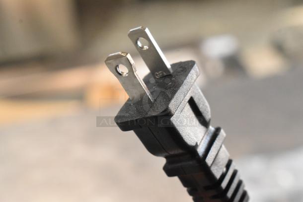 Close-up of a power plug for a Genesis GCS130 circular saw, showcasing standard two-prong design.
