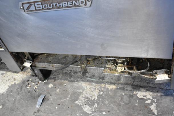 Southbend stainless steel commercial 8 burner range with oven, visible wear, on commercial casters.