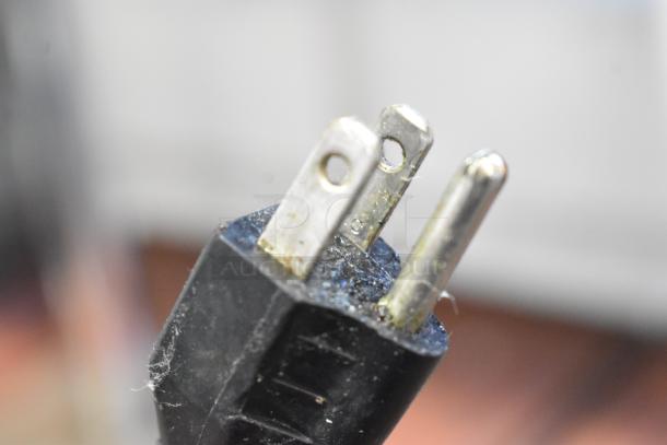 Close-up of a three-prong plug from a Robot Coupe R2N food processor, showing minor wear and use.