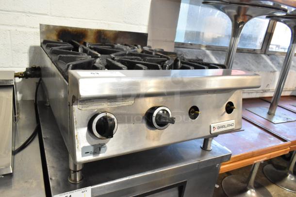 Garland stainless steel commercial gas-powered 4 burner range in used condition, featuring control knobs and a Garland brand label.