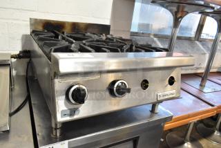 Garland stainless steel commercial gas-powered 4 burner range in used condition, featuring control knobs and a Garland brand label.