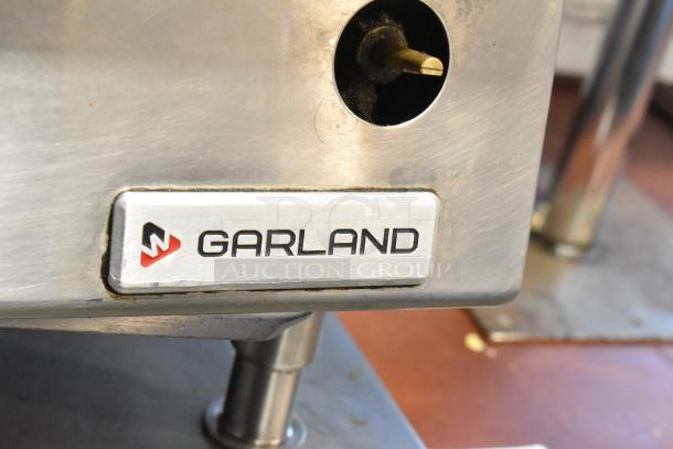 Garland stainless steel commercial gas range, 4 burners, brand logo visible, good condition.
