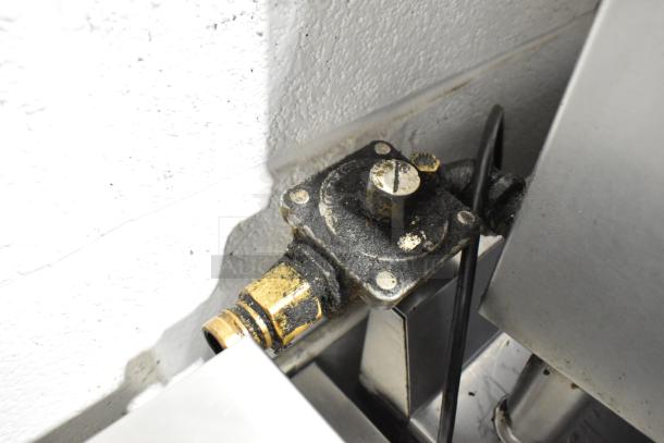 Close-up of a gas fitting on a Garland Stainless Steel Commercial Gas Powered 4 Burner Range, showing wear and use.