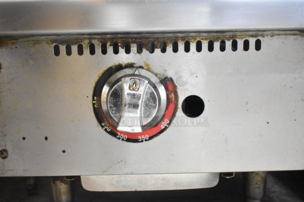 Stainless steel gas-powered flat top griddle with temperature dial, some rust and wear on surface, countertop model.
