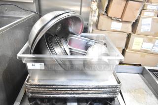 Lot of metal baking pans and bowls in a plastic tub, varied sizes and conditions. Auction tag indicates item number 62.