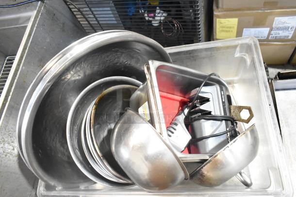 Lot of metal baking pans and bowls in a clear container, includes kitchen utensils and small appliances, used condition.