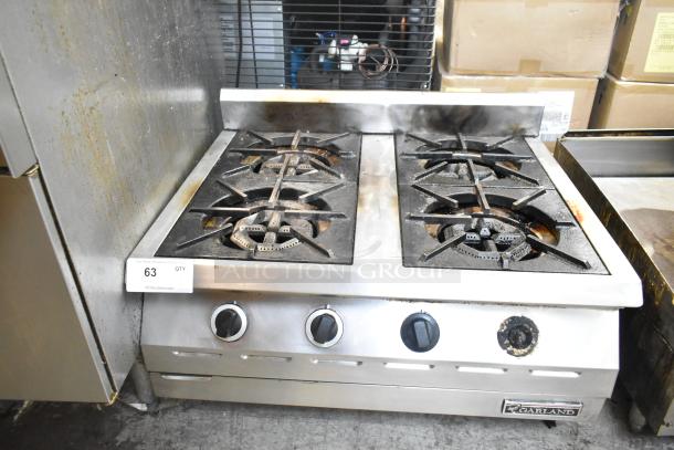 Garland Stainless Steel Commercial Gas 4 Burner Range in used condition, featuring sturdy cast-iron grates and manual controls.