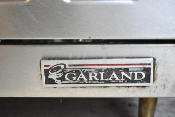 Garland stainless steel commercial gas 4-burner range, featuring brand logo, in used condition.