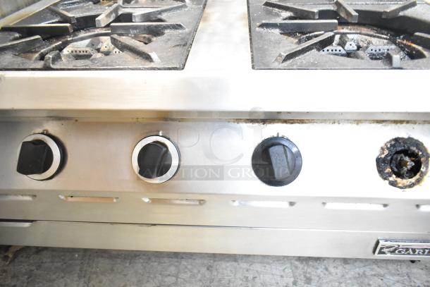 Garland stainless steel commercial gas 4-burner range, showing control knobs, moderate wear, suitable for restaurant use.