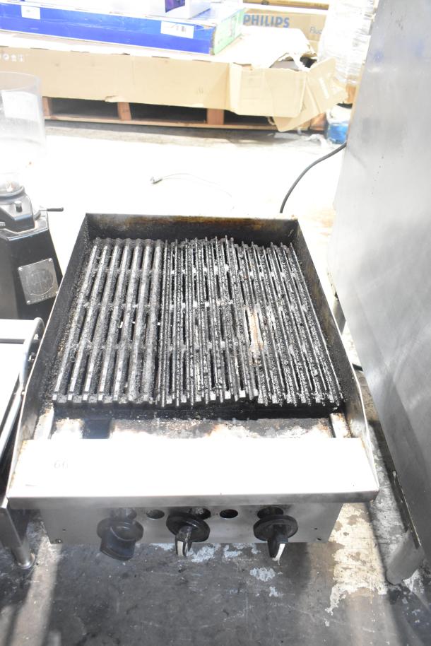Stainless steel commercial countertop gas charbroiler grill with used grates, three control knobs, and sturdy construction.
