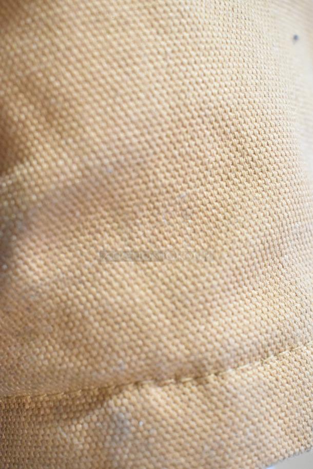 Tan woven fabric texture with close-up stitches. No visible product details or markings.