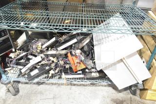 Lot of various ballasts on a metal shelf. Includes mixed models, visible wiring, and some labels. Marks indicate used condition.