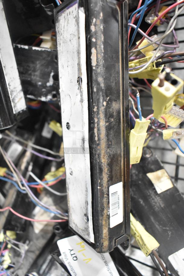 Lot of various ballasts with wires, visible wear and rust, barcode sticker, and auction tag indicating quantity.