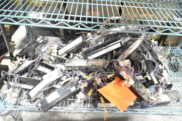 Lot of various ballasts, mixed condition, on storage rack. Includes cables and labels with numbers and identifiers.