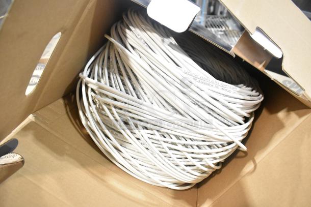 Coiled spool of white wire in a cardboard box, marked "CMG FT4 CL2" and "CM RS-485." Part of a pallet lot auction.