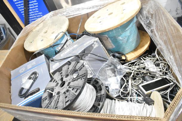 Pallet lot of various items including large spools of wire, several cables, and mixed electronics in fair condition.