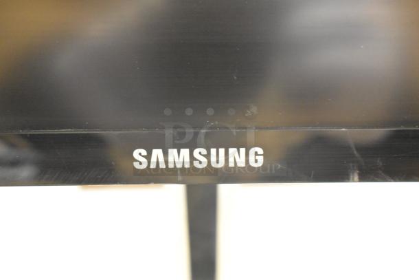Samsung C27F396FHN monitor close-up, showing the brand logo on the black bezel. Part of a 3-monitor auction set.