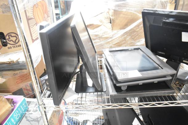 Five computer monitors, including Dell, on metal shelf; mixed models and conditions, visible labels with numbers and tags.