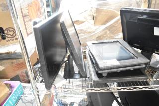 Five computer monitors, including Dell, on metal shelf; mixed models and conditions, visible labels with numbers and tags.