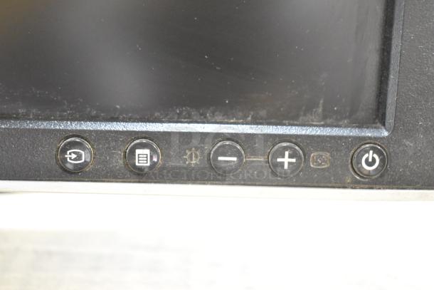 Close-up of computer monitor controls including power, menu, and volume buttons. Condition shows wear and dust.