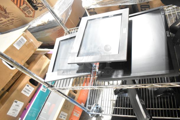 Five computer monitors, including Dell and IBM brands, stacked on a metal shelf. Condition appears used.