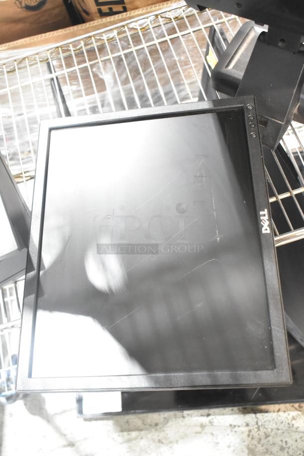 Five computer monitors, including a Dell, displayed on a metal rack. Monitors show wear; Dell logo visible. Multiple bidding set.