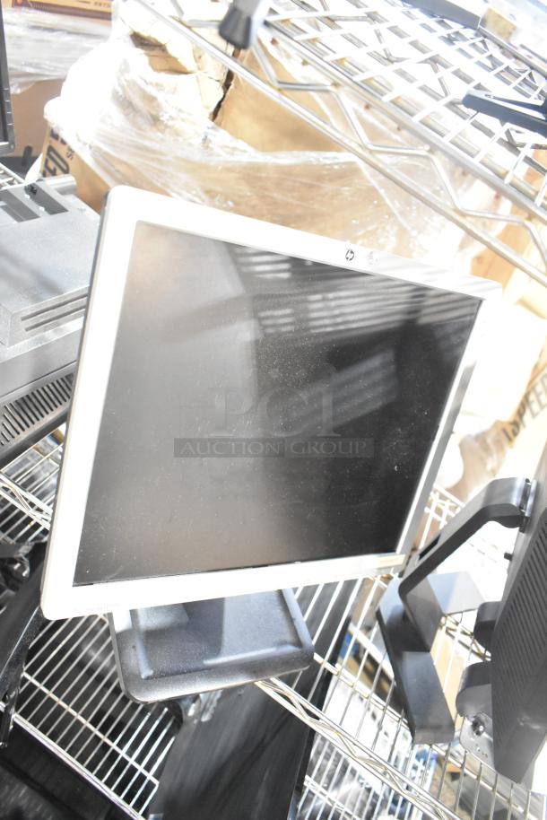 Three computer monitors, including Dell and HP, on a metal shelf. Monitors display some dust, indicating used condition.
