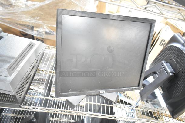 Three computer monitors, including Dell and HP, on a metal shelf. Good condition, black frames, visible Dell logo.