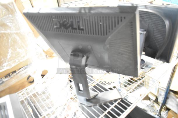 Three computer monitors, including Dell and HP models, on metal shelving. Monitors appear in used condition.