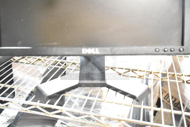 Three computer monitors, including a Dell, displayed on metal shelving. The Dell logo is visible on one monitor.