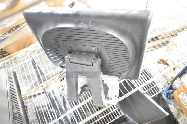 Three computer monitors on a shelf, including Dell and HP. Monitors show back design and stands, with visible HP logo.